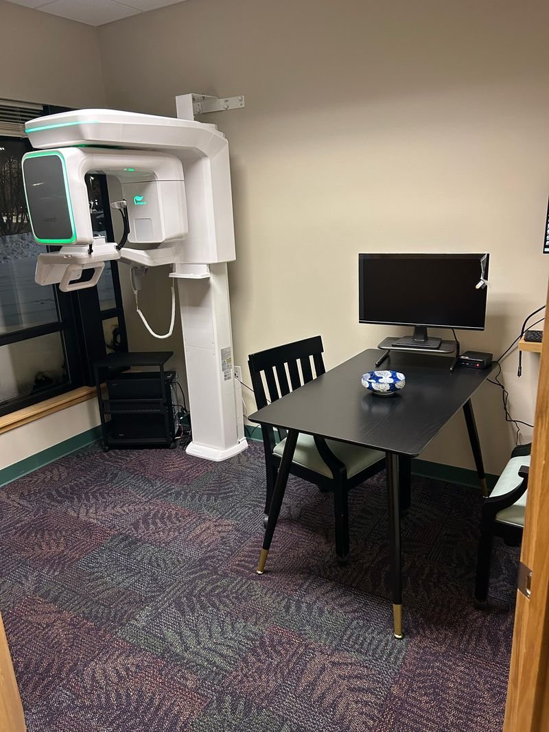 Dental examination room featuring advanced imaging equipment, a computer desk with monitor, and seating, emphasizing comprehensive dental care at Kalamazoo Dental Care.
